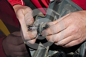 Male hands replacing a light bulb in a car lamp. Man is fixing the car