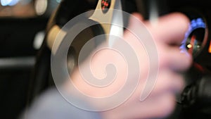 Male hands rotating car steering wheel. Close up of man driving car at night