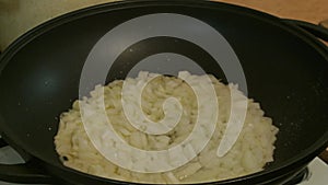 Male hands salted fried onions in a frying pan. Russian cuisine.