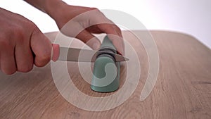 Male hands sharpen a knife with a sharpener. 4k stock footage.