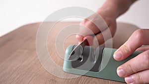 Male hands sharpen a knife with a sharpener. 4k stock footage.