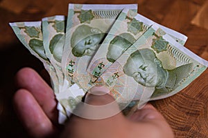 Male hands showing Chinas banknotes, Yuan money on wooden banknotes