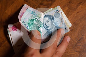 Male hands showing Chinas banknotes, Yuan money on wooden banknotes