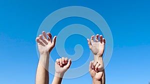 Male hands and small children`s hands close-up against the blue sky. Hands clench and unclench fingers in a farewell