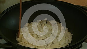 Male hands stir fried onions in a frying pan. Russian cuisine.