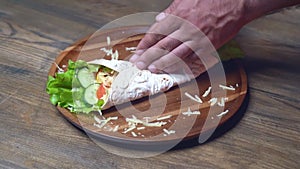 male hands swerve pita with vegetables and cheese. vegetarian roll.