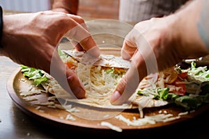 male hands swerve pita with vegetables and cheese. vegetarian roll. photo