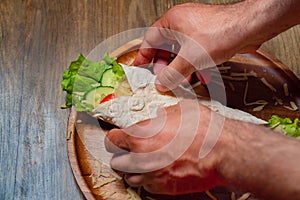 male hands swerve pita with vegetables and cheese. vegetarian roll. photo