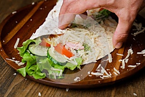 male hands swerve pita with vegetables and cheese. vegetarian roll. photo