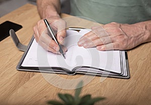 Male hands taking notes, writing plans in notebook or planner. Planning in schedule diary, close up
