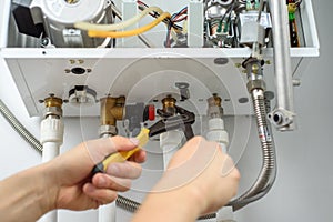 A male hands with tools checks the pipes that fit the gas heating boiler