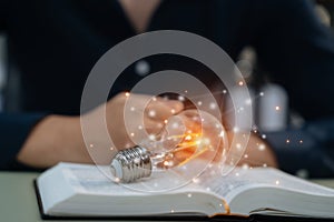 Male hands touching to light bulb which have mechanical gear inside on open book for creative thinking of problem solving and