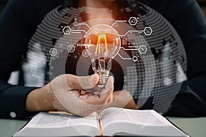 Male hands touching to light bulb which have mechanical gear inside on open book for creative thinking of problem solving and