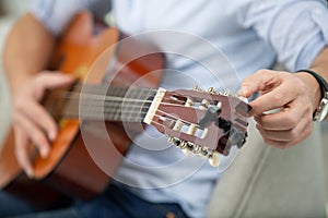 male hands tune acoustic guitar