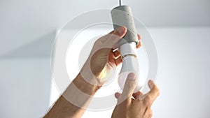 Male hands twisting electrical saving lightbulb, energy efficiency, closeup