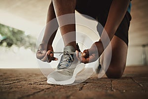 Male hands tying shoelace of running shoes before practice