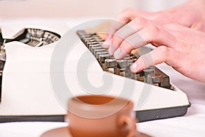 Male hands type story or report using white vintage typewriter equipment close up. Writing routine. Vintage typewriter