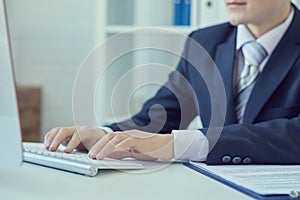 Male hands typing on desktop computer keyboard in office closeup.