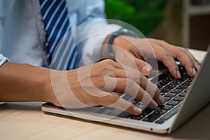 Male hands typing on keyboard laptop at the office.search information form internet working on computer concept for technology