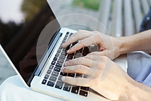 Male hands typing on laptop closeup outdoors