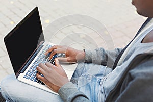 Male hands typing on laptop closeup outdoors