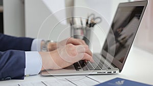 Male hands typing on laptop's keyboard, close-up view