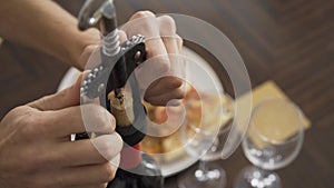 Male hands uncork a bottle of wine with a corkscrew close-up.