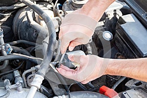 Male hands unscrew the fuel line from the fuel filter with a phillips screwdriver to replace it. Repair and replacement