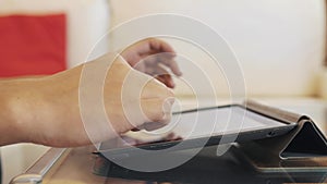 Male hands using cased tabled upon glass coffee table desk, playing video game