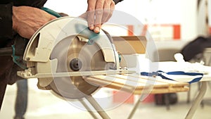 Male hands using circular blade sawing the wooden piece