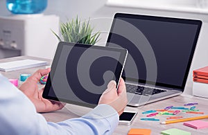 Male hands using ipad digital tablet pc and macbook laptop on the office desk photo