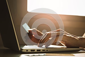 Male hands using laptop computer and holding credit card at working desk for online shopping