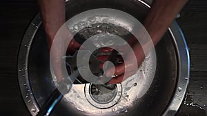 Male hands wash coffee maker in a sink top view