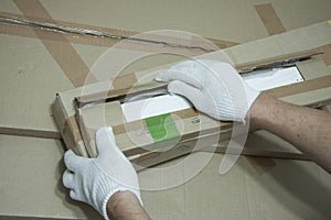 Male hands in white gloves with a knife unpack the box.