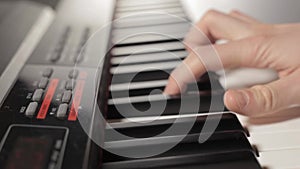 Male hands with white sleeves play the digital piano.