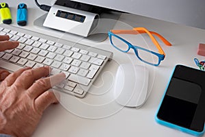 Male hands work on the computer keyboard - white desk