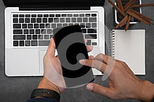 Male hands working on modern samrtphone and laptop. Office desktop on Cement wall background