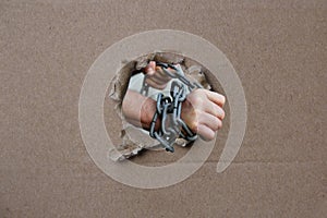 Male hands wrapped in a thick heavy iron chain, a symbol of the arrest of a criminal