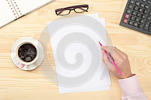 Male hands writing on empty blank paper over wooden table. Businessman working with documents. Clipboard mockup template paperwork