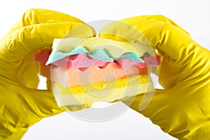 Male hands in yelliw gloves holding a burger made from sponges different colors. Concept of unhealthy food and non