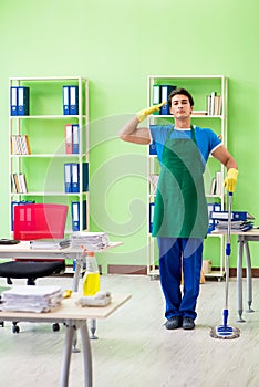 The male handsome professional cleaner doing mopping in the office