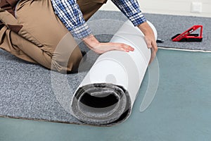 Male Handyman Rolling Carpet On Floor