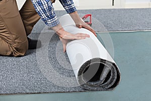 Male Handyman Rolling Carpet On Floor