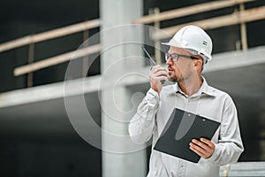 Male head engineer wearing white safety hardhat with walkie talk