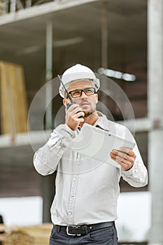 Male head engineer wearing white safety hardhat with walkie talk