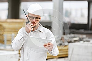 Male head engineer wearing white safety hardhat with walkie talk