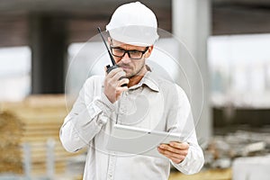 Male head engineer wearing white safety hardhat with walkie talk