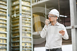 Male head engineer wearing white safety hardhat with walkie talk