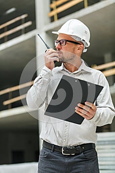 Male head engineer wearing white safety hardhat with walkie talk
