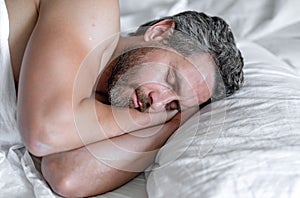 Male head on pillow. Gray hair man sleep in white bed. Senior man sleep in bed at bedroom. Mature man sleeps at home at